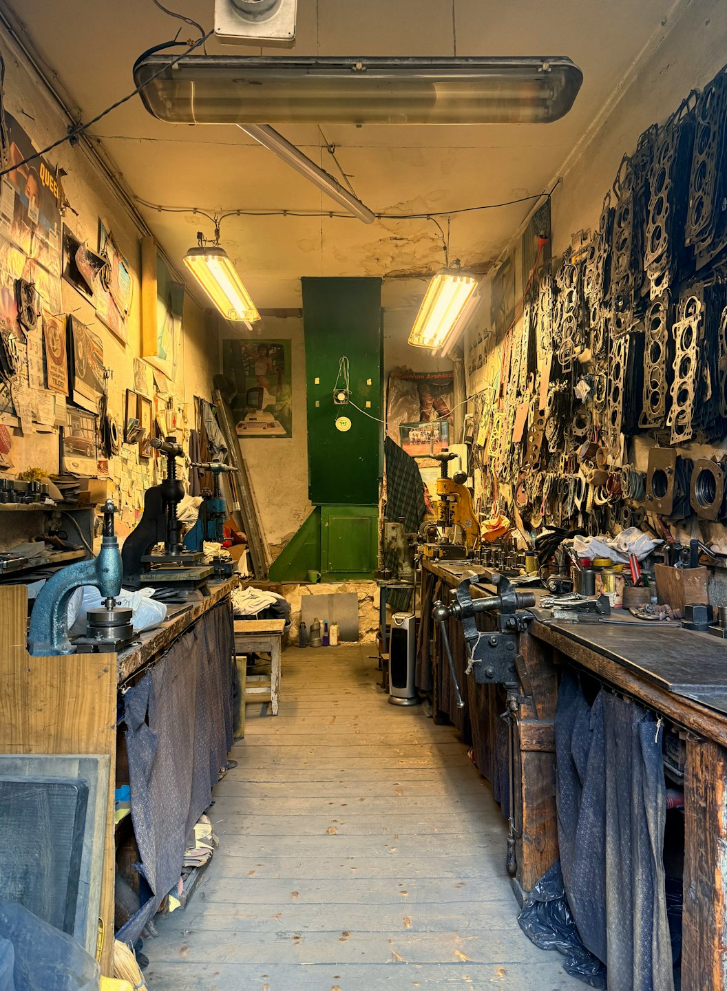 Tools and metal parts clutter a narrow workshop interior.