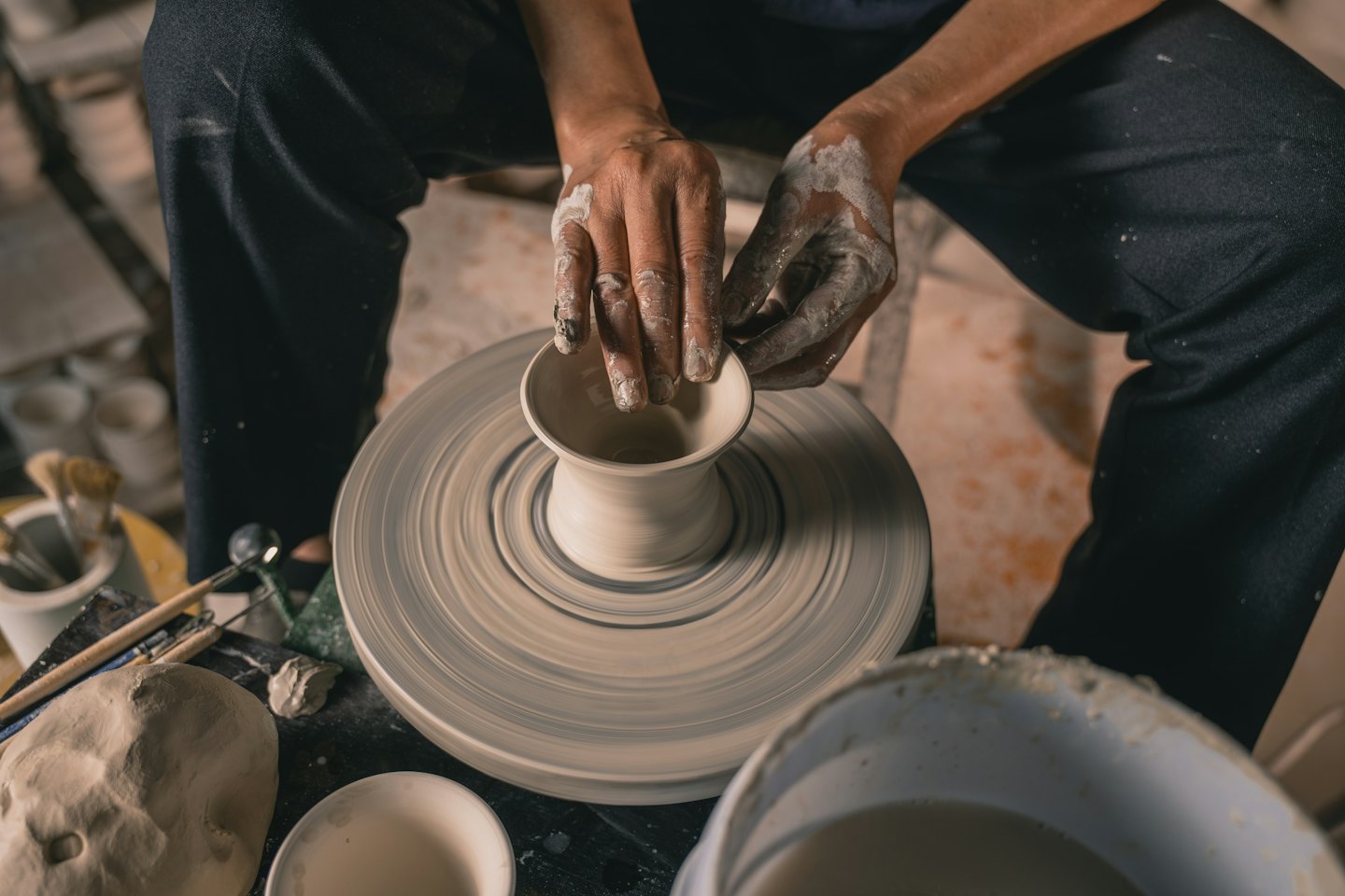Hands shaping clay on a pottery wheel in a workshop.